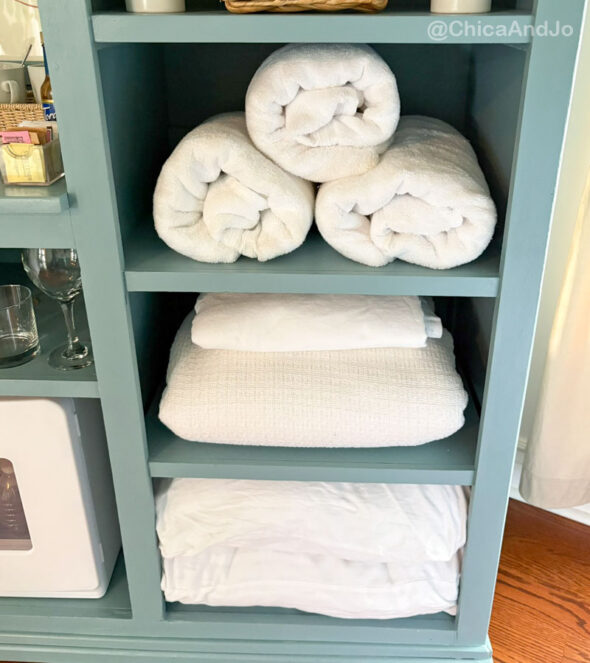 guest room essentials in a thrifted cabinet for amenities - extra linens and towels